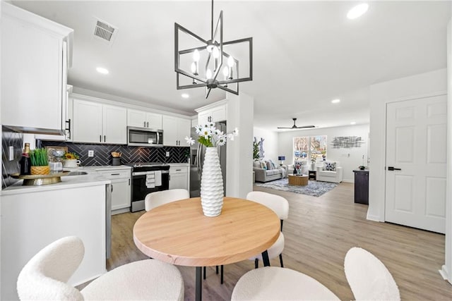 dining area with ceiling fan with notable chandelier, light wood-style flooring, recessed lighting, and visible vents