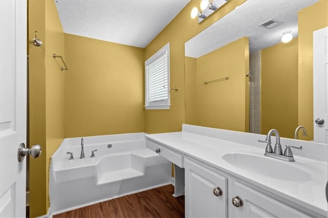 305 Hickory Pointe Ct, Villa Rica, GA 30180 - bathroom with wood finished floors, a garden tub, vanity, a textured ceiling, and a shower