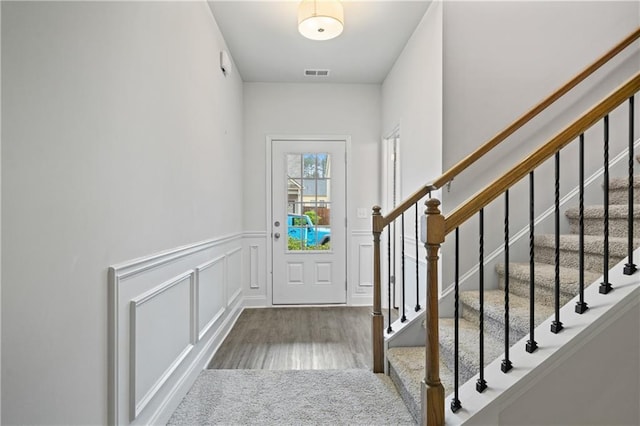 61 Castlemoor Loop, Adairsville, GA 30103 - doorway to outside featuring a wainscoted wall, wood finished floors, visible vents, a decorative wall, and stairs