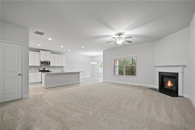 61 Castlemoor Loop, Adairsville, GA 30103 - unfurnished living room featuring a fireplace with flush hearth, visible vents, light colored carpet, and ceiling fan with notable chandelier