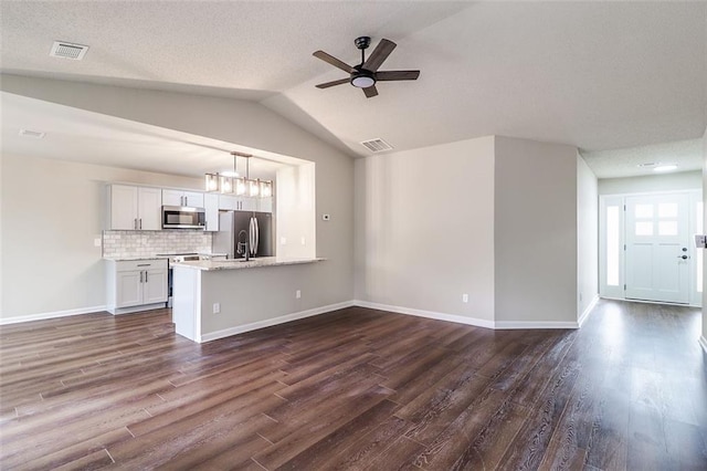 unfurnished living room with a textured ceiling, dark wood-type flooring, and vaulted ceiling