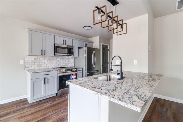 kitchen featuring stainless steel appliances, light stone counters, dark wood-type flooring, and sink