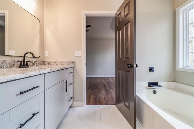 bathroom featuring hardwood / wood-style flooring, plenty of natural light, a tub to relax in, and vanity