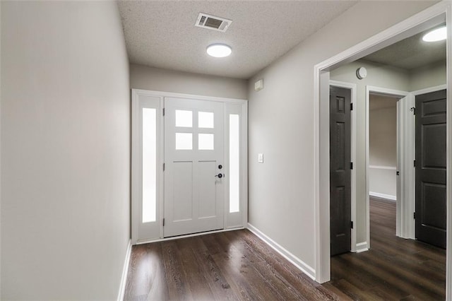 foyer with dark wood-type flooring and a textured ceiling