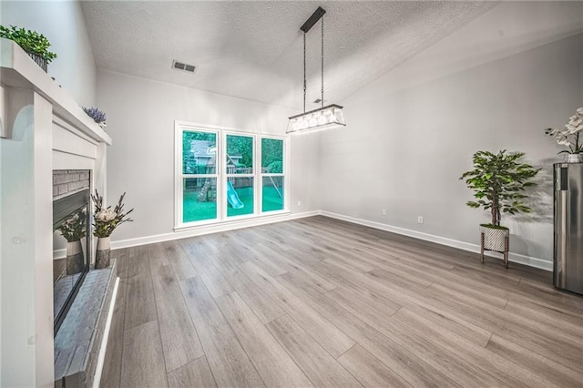 220 Chandler Ct, Sugar Hill, GA 30518 - unfurnished living room with a brick fireplace, wood finished floors, a textured ceiling, and a chandelier