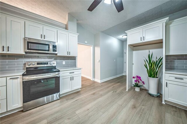 220 Chandler Ct, Sugar Hill, GA 30518 - kitchen with appliances with stainless steel finishes, light countertops, a ceiling fan, light wood-type flooring, and vaulted ceiling