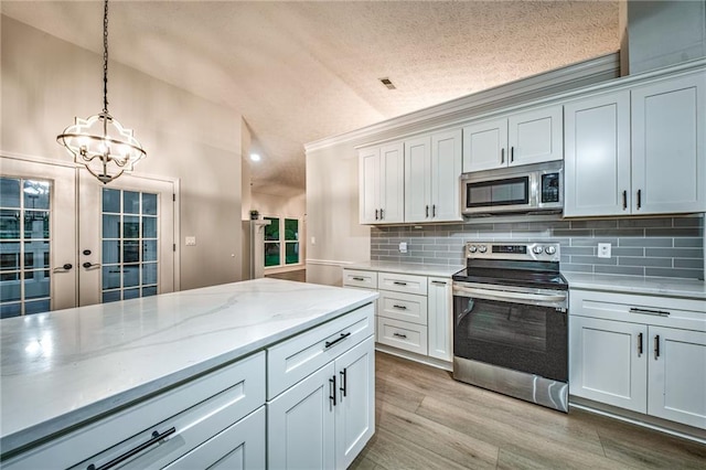 220 Chandler Ct, Sugar Hill, GA 30518 - kitchen with appliances with stainless steel finishes, a chandelier, vaulted ceiling, tasteful backsplash, and hanging light fixtures