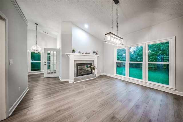 220 Chandler Ct, Sugar Hill, GA 30518 - unfurnished living room featuring a chandelier, wood finished floors, lofted ceiling, a textured ceiling, and a brick fireplace