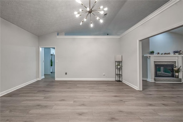 220 Chandler Ct, Sugar Hill, GA 30518 - empty room featuring a chandelier, a textured ceiling, wood finished floors, lofted ceiling, and a brick fireplace
