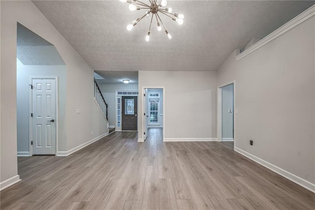 220 Chandler Ct, Sugar Hill, GA 30518 - unfurnished living room with a textured ceiling, wood finished floors, stairway, and a chandelier
