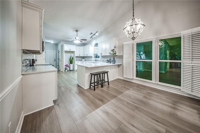 220 Chandler Ct, Sugar Hill, GA 30518 - kitchen featuring a peninsula, lofted ceiling, wood finished floors, a chandelier, and backsplash