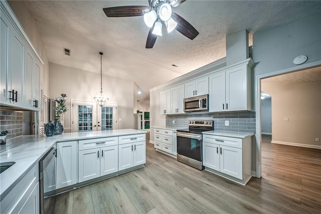 220 Chandler Ct, Sugar Hill, GA 30518 - kitchen featuring stainless steel appliances, a peninsula, tasteful backsplash, light wood finished floors, and a textured ceiling