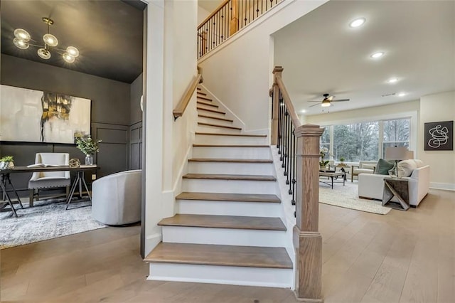 staircase featuring ceiling fan and hardwood / wood-style floors