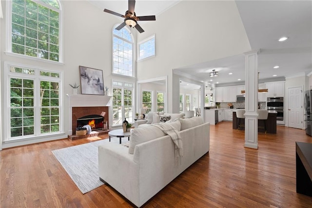 735 River Ridge Lane, Suwanee, GA 30024 - living area featuring decorative columns, a warm lit fireplace, ceiling fan, crown molding, and wood finished floors