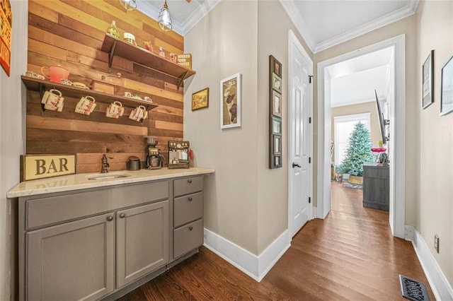 bar with crown molding, wooden walls, gray cabinets, and sink