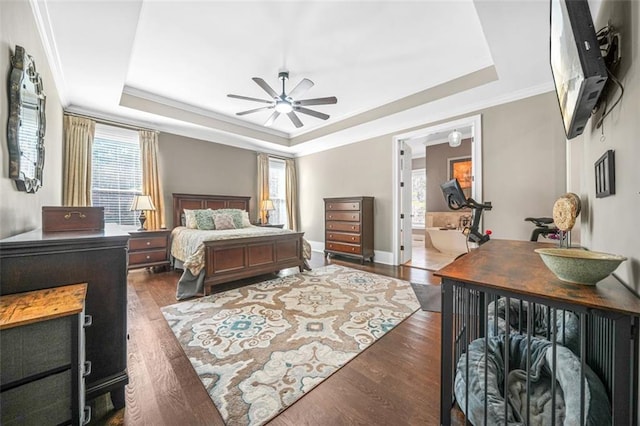 bedroom with ceiling fan, connected bathroom, a tray ceiling, and multiple windows