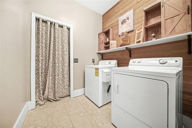 washroom with separate washer and dryer, a textured ceiling, and wood walls