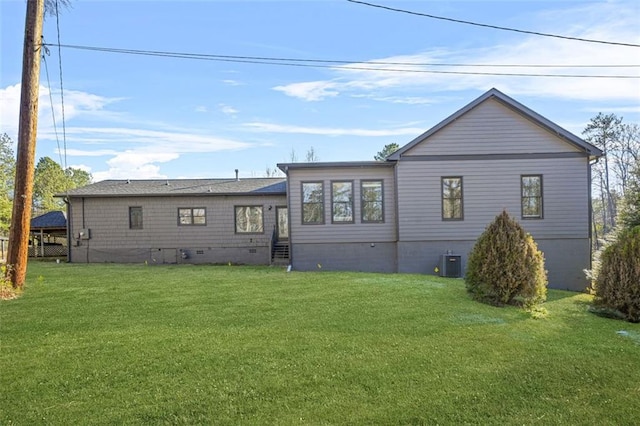 rear view of house with central AC and a lawn