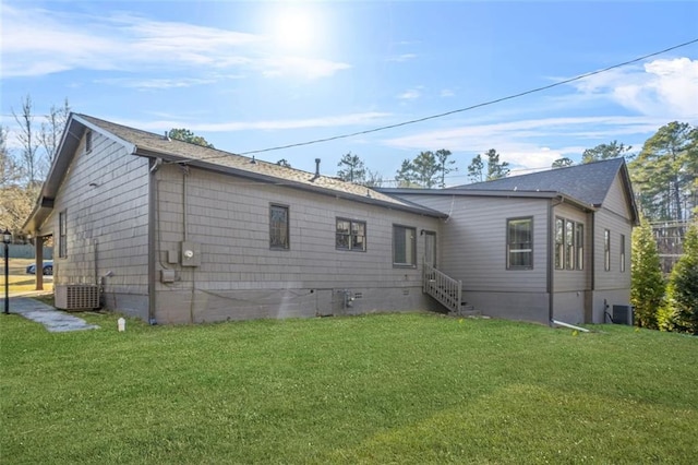 rear view of property featuring central AC and a yard