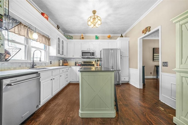 kitchen featuring stainless steel appliances, ornamental molding, tasteful backsplash, and white cabinets