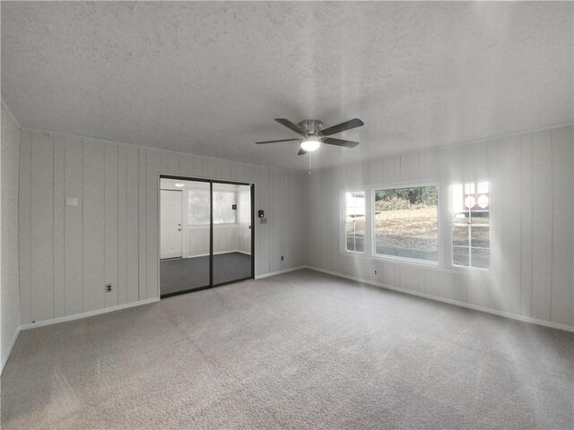 carpeted empty room with a textured ceiling and ceiling fan