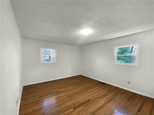 unfurnished room with a wealth of natural light and dark wood-type flooring