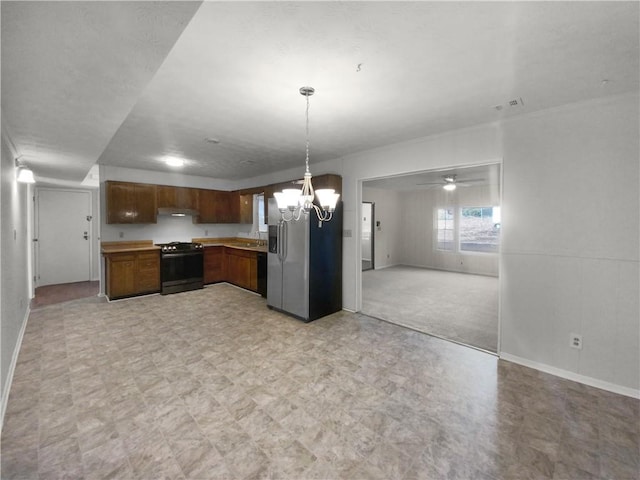 kitchen with a wood stove, a textured ceiling, light colored carpet, stainless steel appliances, and a chandelier