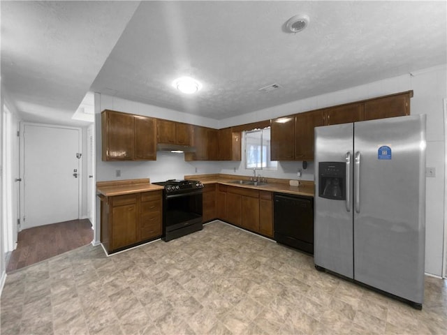 kitchen with light carpet, stainless steel refrigerator with ice dispenser, black range oven, ceiling fan with notable chandelier, and hanging light fixtures