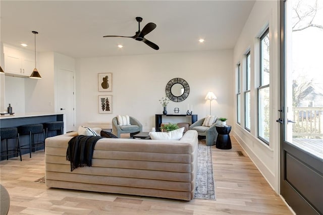 living room with ceiling fan, light wood-type flooring, and a healthy amount of sunlight