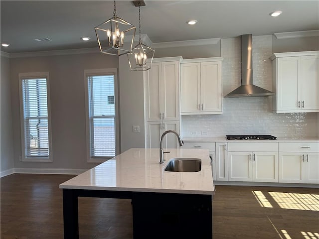 kitchen with wall chimney range hood, ornamental molding, gas stovetop, and a sink