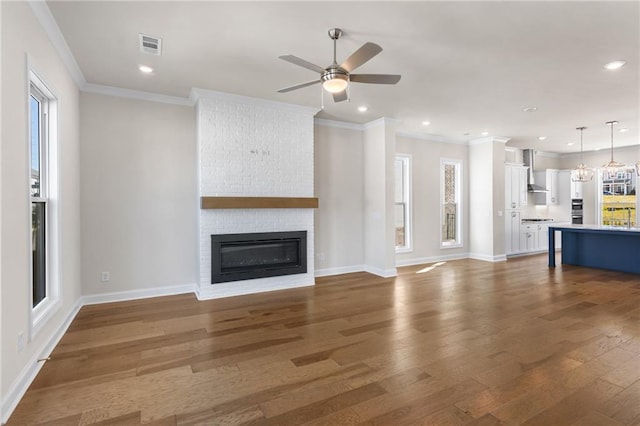 unfurnished living room featuring a fireplace, wood finished floors, baseboards, and ornamental molding