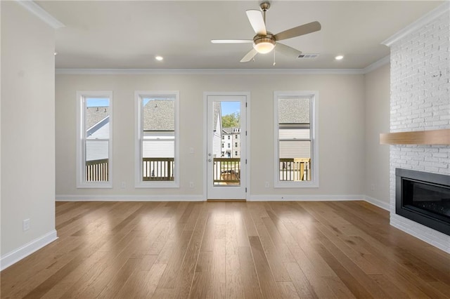 unfurnished living room with baseboards, wood finished floors, a fireplace, and crown molding