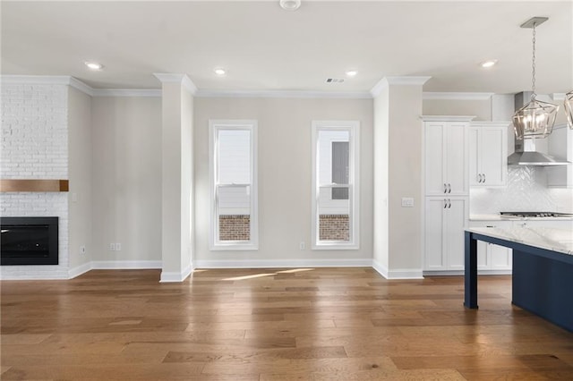 175 Basil St, Cumming, GA 30040 - unfurnished living room with wood finished floors, crown molding, recessed lighting, a brick fireplace, and a chandelier
