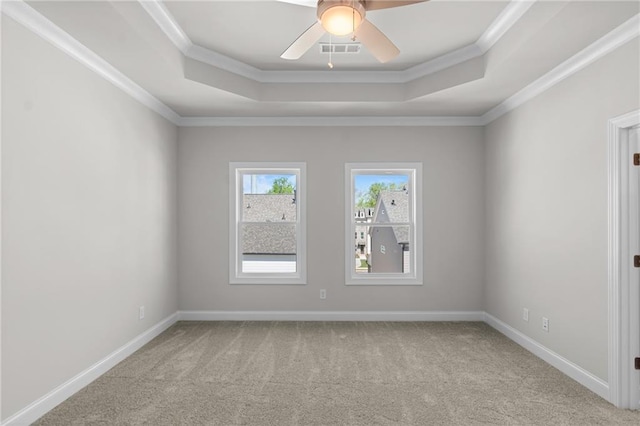 empty room featuring a tray ceiling, visible vents, carpet, and crown molding