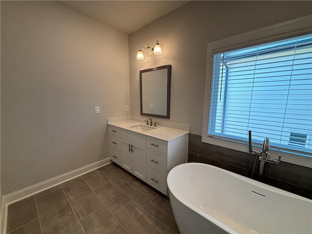 full bathroom featuring baseboards, a freestanding bath, and vanity