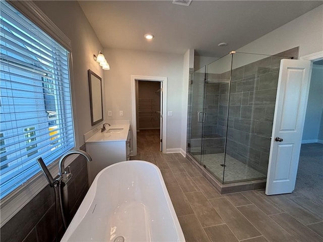 full bathroom featuring a spacious closet, visible vents, a shower stall, baseboards, and a freestanding bath