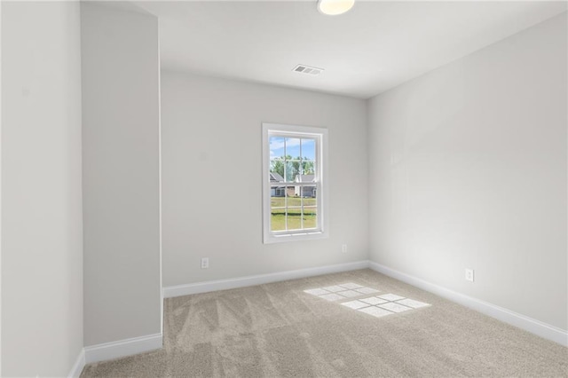 spare room featuring visible vents, light colored carpet, and baseboards