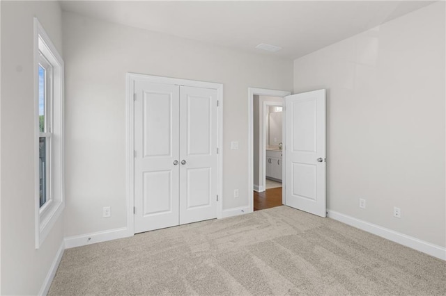 unfurnished bedroom with a closet, carpet floors, and baseboards