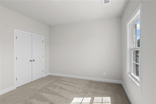 unfurnished bedroom with a closet, carpet flooring, baseboards, and visible vents