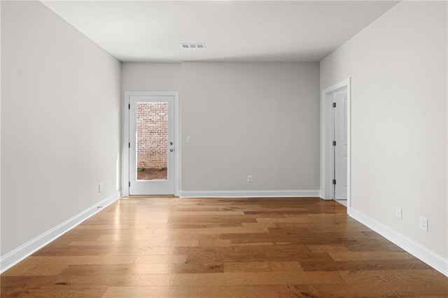 spare room featuring visible vents, baseboards, and wood finished floors