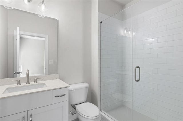 bathroom with vanity, a shower stall, and toilet