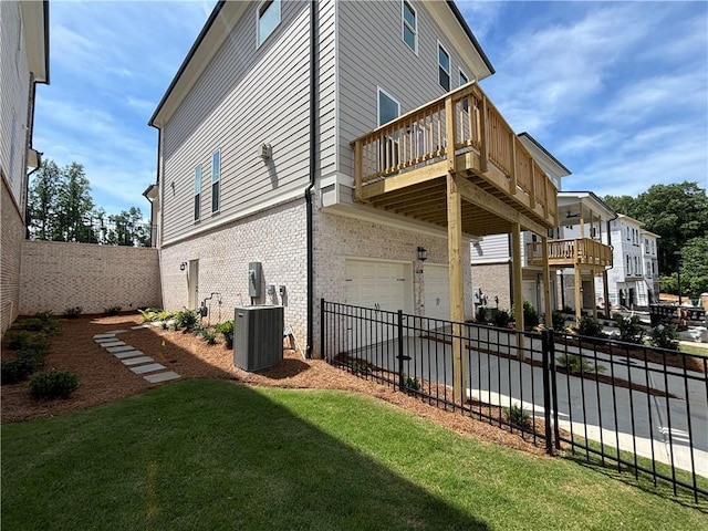 view of home's exterior featuring central air condition unit, a lawn, fence, an attached garage, and brick siding