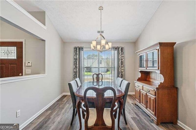 2350 Laurel Pointe Ln, Lawrenceville, GA 30043 - dining area featuring a chandelier, vaulted ceiling, dark wood-style flooring, baseboards, and a textured ceiling