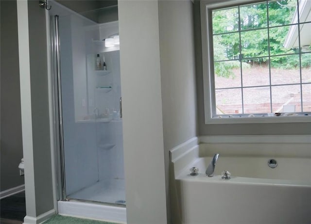 2350 Laurel Pointe Ln, Lawrenceville, GA 30043 - bathroom featuring a shower stall, healthy amount of natural light, a bath, and baseboards