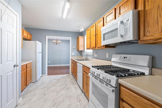 kitchen featuring sink, a chandelier, a textured ceiling, and white appliances