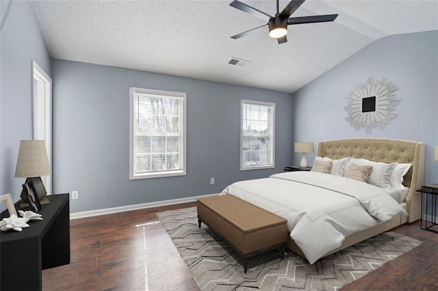 bedroom with dark wood-type flooring, ceiling fan, lofted ceiling, and a textured ceiling