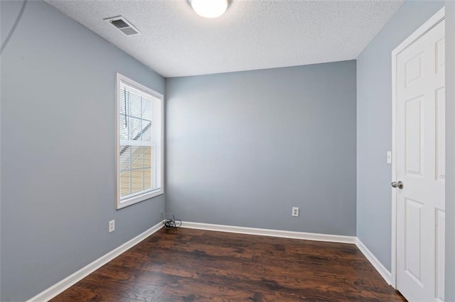 spare room featuring dark hardwood / wood-style flooring and a textured ceiling