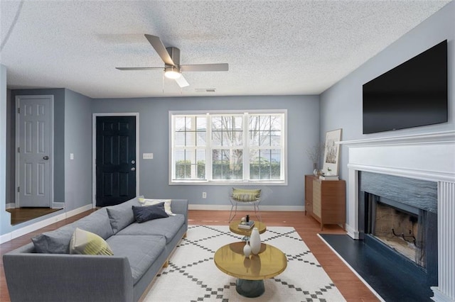 living room with wood-type flooring, ceiling fan, and a textured ceiling