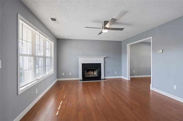 unfurnished living room featuring ceiling fan, dark hardwood / wood-style flooring, and a textured ceiling