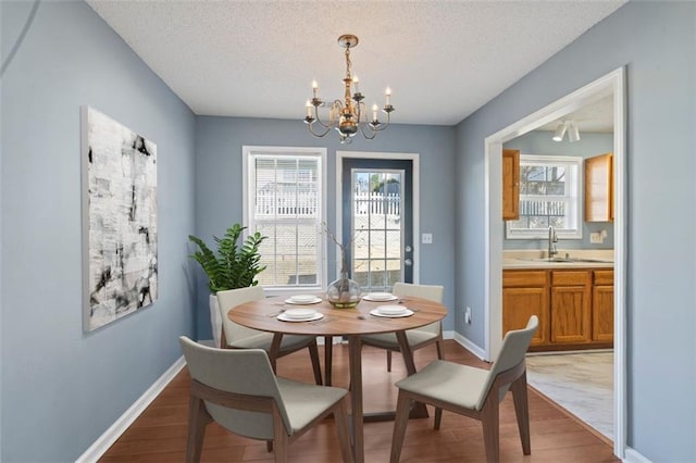 dining space featuring hardwood / wood-style flooring, a chandelier, sink, and a textured ceiling